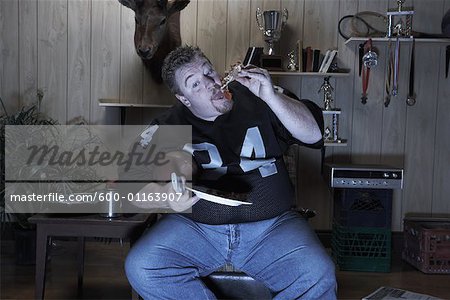 Man Watching Football Game on Television and Eating Pizza
