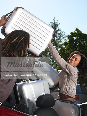 Man Loading Suitcase into Woman's Car