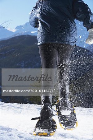Femme en cours d'exécution avec les raquettes à neige