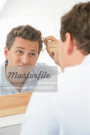 Man Examining Hair in Mirror
