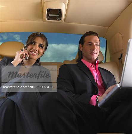 Businesswoman on Cell Phone and Businessman using Laptop, in Limo