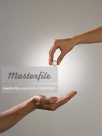 Woman holding coin above mans hand Woman holding coin above mans hand