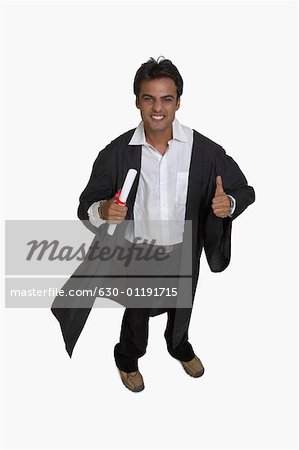 Portrait of a college student holding his diploma and showing thumbs up sign