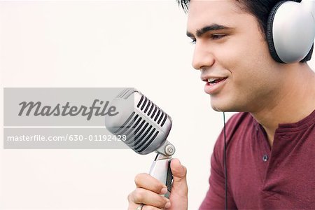 Gros plan d'un jeune homme chanter dans un microphone