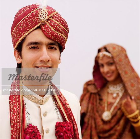 Close-up of a groom smiling with his bride standing behind him