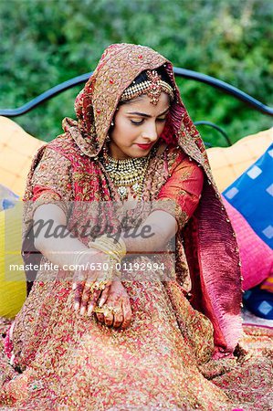 Bride in a traditional wedding dress sitting on the bed in a lawn
