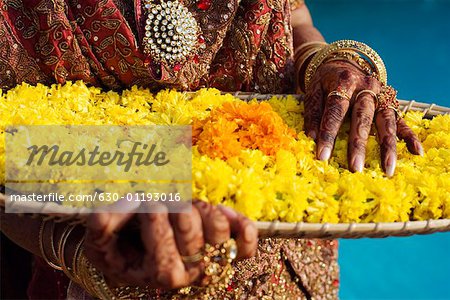 Mid section view of a bride holding a tray of flower garlands