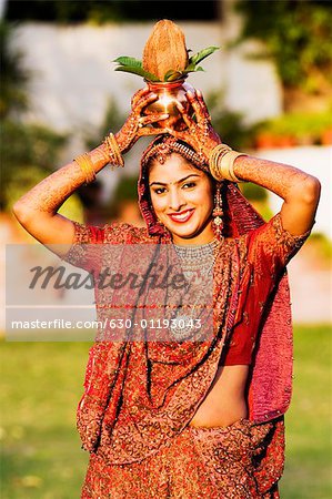 Portrait of a bride holding a vessel and a coconut on her head