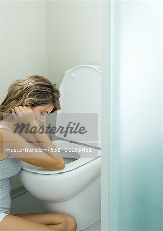 Young woman sitting next to toilet