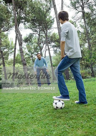 Mature man and teenage boy playing soccer