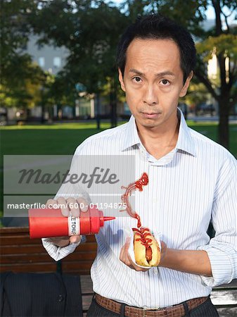 Mann mit Hotdog Spritzen Ketchup auf Hemd
