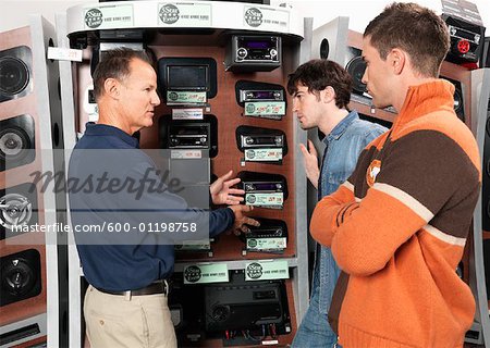 Deux hommes à l'écoute de vendeur en magasin d'électronique