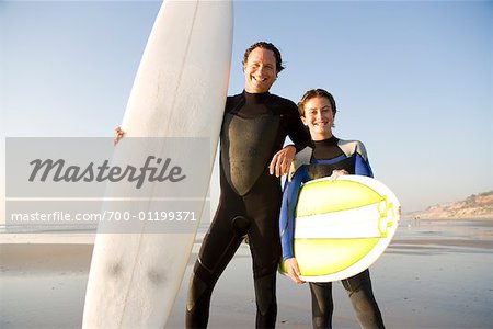 Père et fils à la plage avec des planches de surf