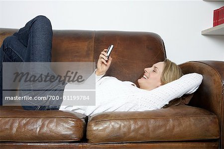 Femme avec téléphone cellulaire sur le canapé
