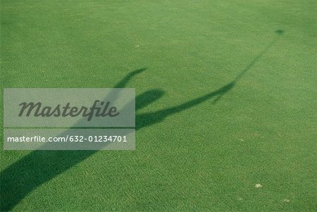 Shadow of golfer raising arms