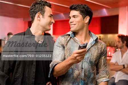 Männer betrachten Handy in Nachtclub