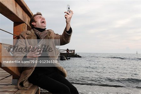 Man Using Cellular Phone and Laughing