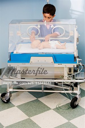 Boy touching a baby boy in an incubator