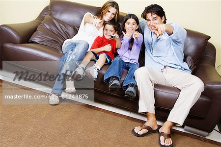 Mid adult couple with their children sitting on a couch and watching television