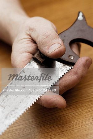 Close-up of a person's hand holding a saw