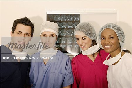 Portrait of a male surgeon and three female surgeons standing in front of an MRI scan