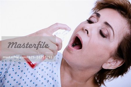 Close-up of a senior woman spraying mouthwash into her mouth