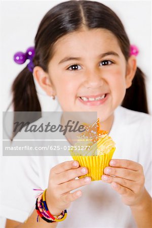 Portrait of a girl holding a cupcake and smiling
