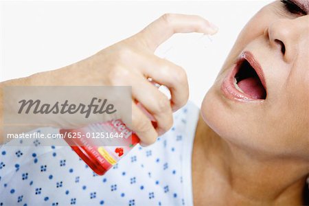 Close-up of a senior woman spraying mouthwash into her mouth