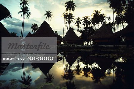 Reflection of huts and trees in water, Huahine Island, French Polynesia