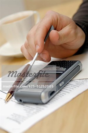 Close-up of a person's hand operating a personal data assistant