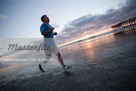 Homme avec une jambe artificielle en cours d'exécution sur la plage