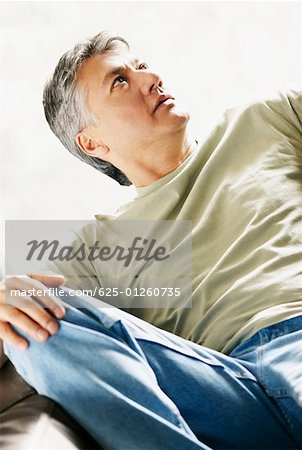 Close-up of a senior man reclining on a couch and thinking