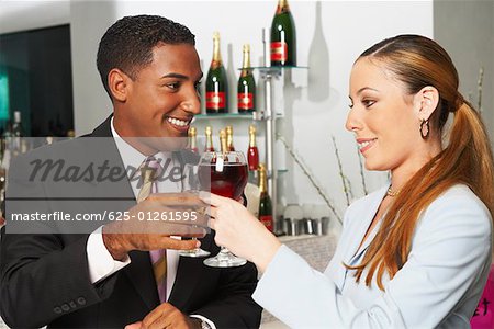 Close-up of a businessman and a businesswoman toasting with wine glasses