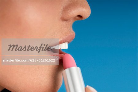 Close-up of a young woman applying lipstick
