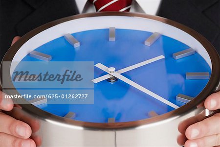Mid section view of a businessman holding a clock