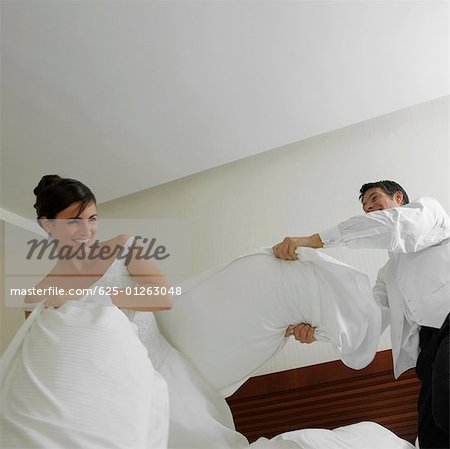 Brautpaar mit einen Kissen auf dem Bett zu kämpfen