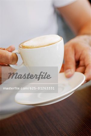 Mid section view of a person holding a coffee cup