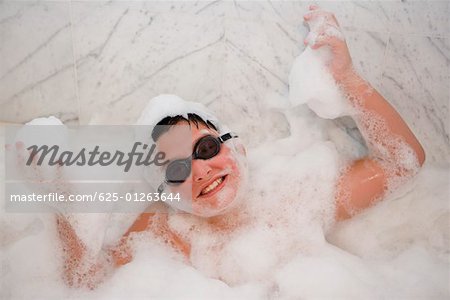 Vue grand angle sur un garçon souriant dans un bain moussant