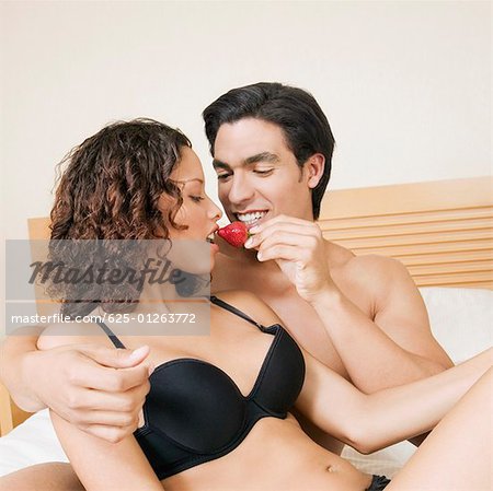 Close-up of a young man feeding a strawberry to a teenage girl