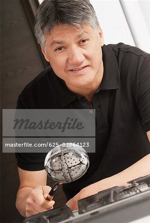 Portrait of a senior man holding a ladle over a burner and smiling