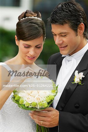 Close-up of a newlywed couple looking at a bouquet of flowers