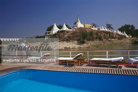 Vue arrière d'un couple debout sur un bateau de croisière et en regardant une pagode, Kyet encore pagode Shwe, Mandalay, Myanmar