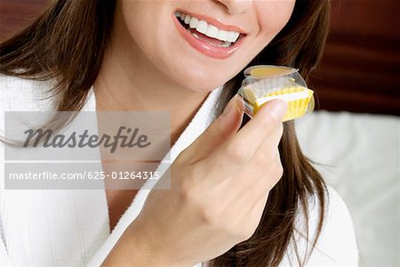 Close-up of a young woman holding a cupcake and smiling