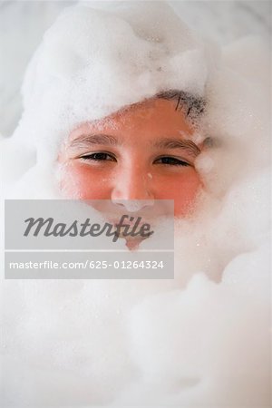 Portrait d'un garçon souriant dans un bain moussant