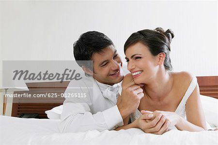 Nahaufnahme von einem frisch verheirateten Paar auf dem Bett liegend und Lächeln