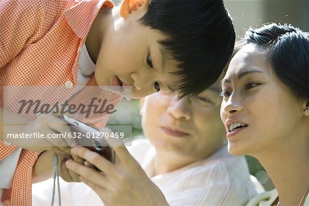 Boy with parents, mother holding digital camera, boy bending over to look