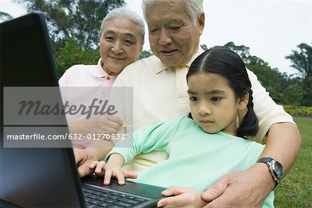 Girl and grandparents using laptop