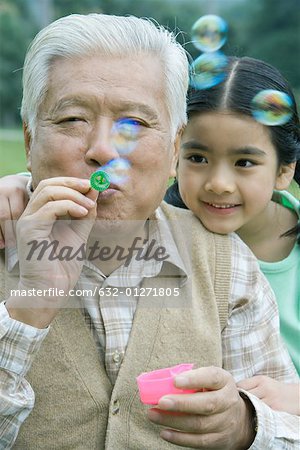 Girl with grandfather blowing bubbles