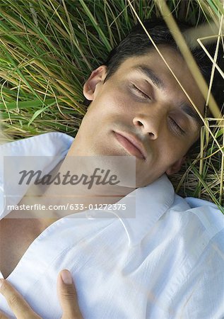 Man sleeping in tall grass, close-up
