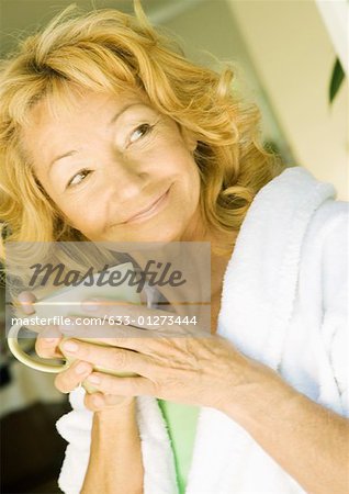 Senior woman wearing bathrobe and holding mug